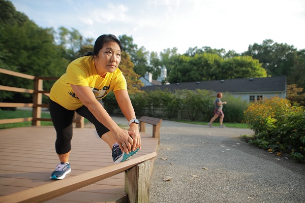 A person in running clothes stretching their legs outdoors